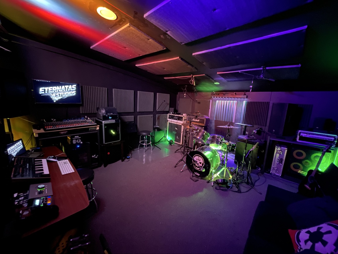 Inside Eternatas Studios — the full room: workstation and mixer, logo screen, current 6-piece Mapex kit and backline under DMX lighting